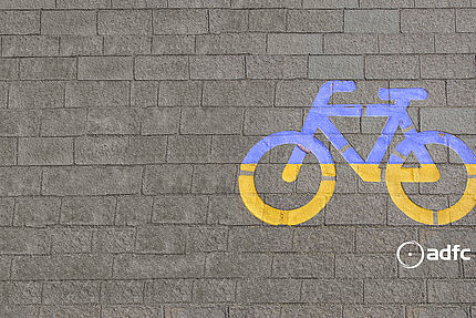 Grafik eines Fahrrads in blau-gelb auf Asphaltboden